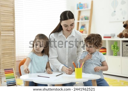 Mother and her little children drawing with colorful pencils at home