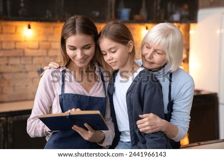 Happy caucasian family reading book together at home kitchen. Horizontal shot of tree generation of women which watching family photo album in cozy interior background