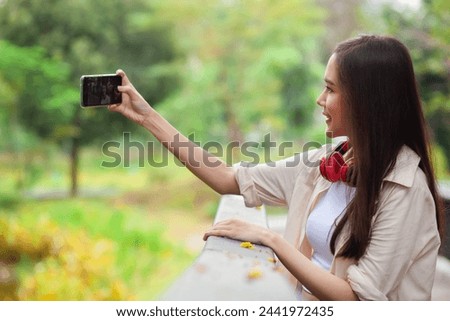 A woman is taking a picture of herself with her cell phone. She is smiling and she is enjoying the moment