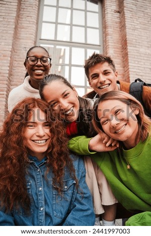 Vertical portrait of a group of friends having fun and smiling together. High school students looking at camera with happy expression. Young friendly real people staring front posing for a photo. High