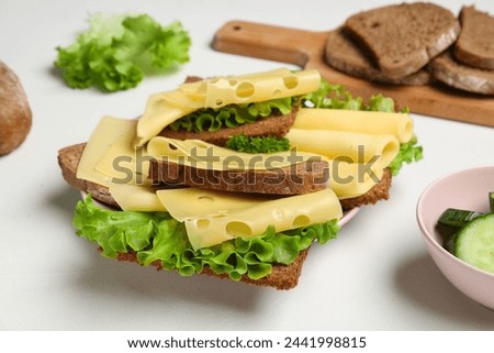 Tasty sandwiches with cheese and lettuce on light background, closeup Royalty-Free Stock Photo #2441998815