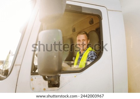 Truck driver job. Logistics - proud driver or forwarder on truck and trailer, on a transshipment point. Transportation service. Royalty-Free Stock Photo #2442003967