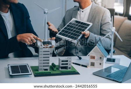 Two Young Engineers Expertise in Solar Cell Installation Meetings and Discussion in The Job. Planning to Install Solar Photovoltaic Panels on Roof Top in The Office Room with Factory Building Plan.