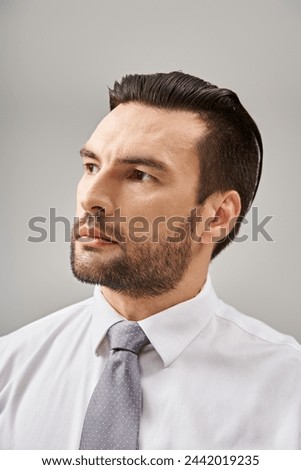 portrait of handsome businessman in white shirt and tie posing with confidence on grey background