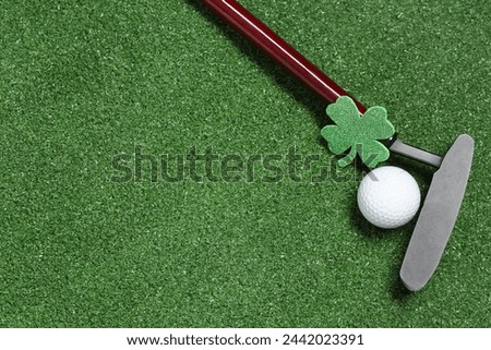 Golf club, ball and clover on green grass background. St. Patrick's Day celebration