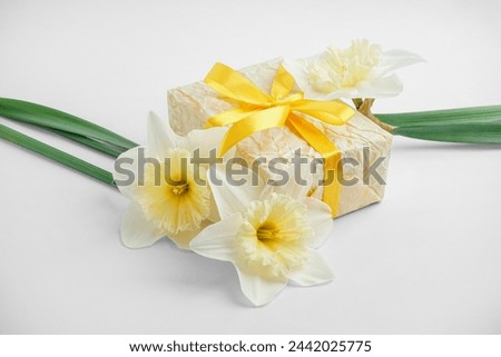 Gift box with daffodil flowers on white background