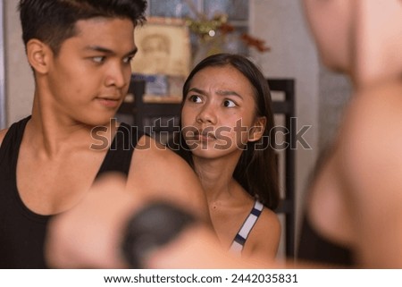 In a tense home scene, a young Asian woman intervenes to stop her angry brother from confronting her abusive boyfriend, showcasing a moment of protection and conflict. Royalty-Free Stock Photo #2442035831