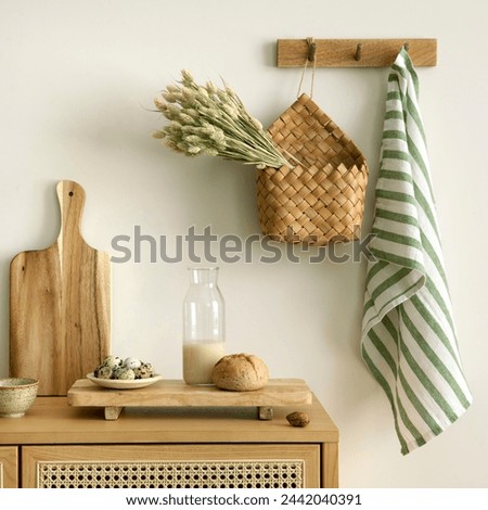 Interior design of kitchen space with rattan commode, cutting board, hanger, basket with dried herbs, vegetables, food, bread, milk and kitchen accessories. Home decor. Template. 