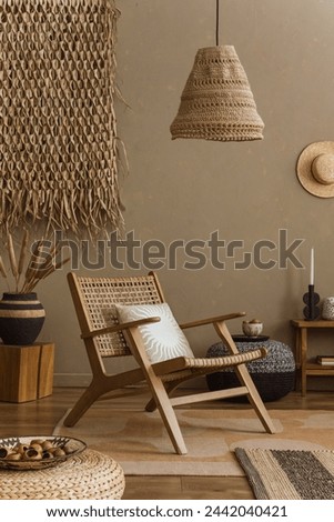 Interior design of ethno style living room with rattan armchair, pouf, hanging decoration on the wall, lamp and elegant personal accessories. Home decor. Template.	
 Royalty-Free Stock Photo #2442040421