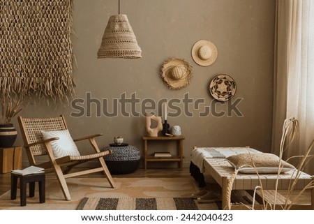 Interior design of ethno style living room with rattan furniture, daybed, pouf, hanging decoration on the wall, lamp and elegant personal accessories. Home decor. Template.	 Royalty-Free Stock Photo #2442040423