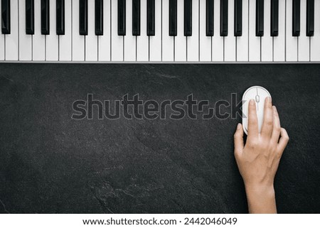 Musical black background with piano keyboard and computer mouse in female hand, flat lay. Music recording studio concept, copy space.