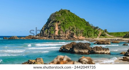 Australian coast, big rock on the seashore surrounded by the sea with big waves, view from the beach to the seaside landscape on a summer evening.