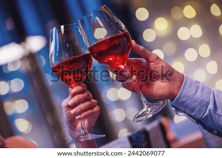 Cropped image of couple clinking glasses of wine together while having a date in a restaurant