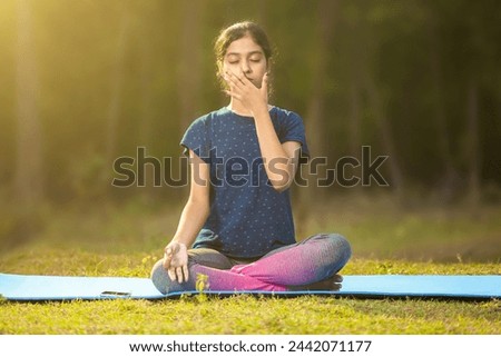 indian ethnicity women concentrating on pranayama meditation by focusing on breath inhale and exhale and sitting in a ardha padmasana position, eyes closed Royalty-Free Stock Photo #2442071177
