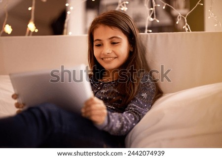 Girl, kid and tablet, happy with tech and relax on sofa with ebook for reading and social media at home. Elearning, cartoon or storytelling app with internet, browsing and digital platform for gaming