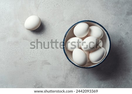 White eggs in a bowl on gray rustic background. Shot from directly above.