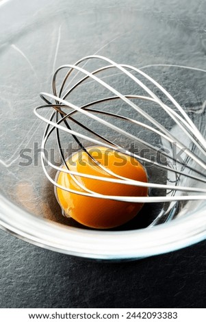 Egg yolk with a whisk in glass bowl, close up shot