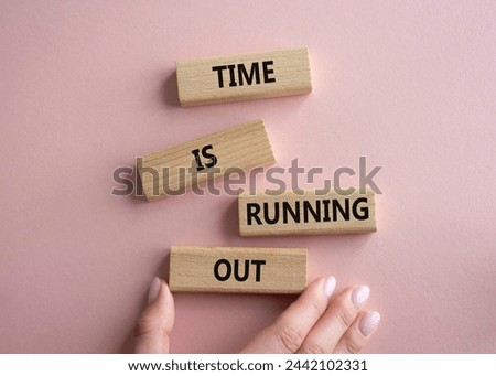 Time is running out symbol. Concept words Time is running out on wooden blocks. Beautiful pink background. Businessman hand. Business and Time concept. Copy space.