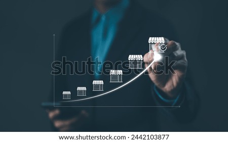 Franchise concept. Franchise Business Growth and Expansion Strategy Visualization. Entrepreneur visualizing franchise growth trajectory with increasing store icons on a digital upward trend graph.