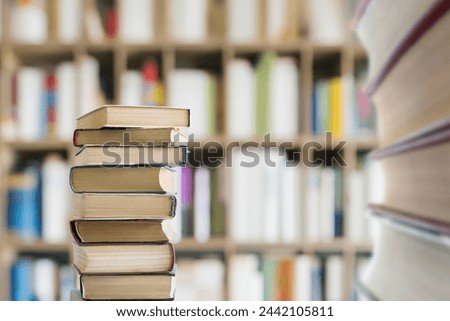 A stack of textbooks against a background of bookshelves in a library. Royalty-Free Stock Photo #2442105811