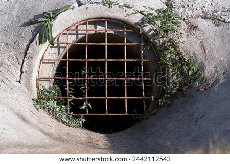 A culvert under the highway with a metal grate at the entrance.                               