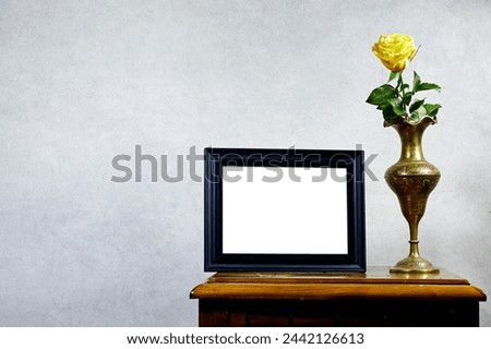 empty picture frame mockup and yellow rose flower vase on wooden table near grunge wall, autumn fall concept