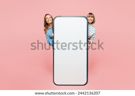 Full body elder parent mom young adult daughter two women wear blue casual clothes behind big huge blank screen area mobile cell phone smartphone isolated on plain pink background. Family day concept