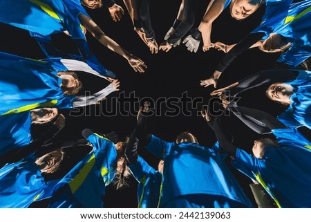 low angle view of football player girls standing in a circle and holding hands up before a match. High quality photo