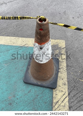 Old and deteriorated traffic cone with safety line