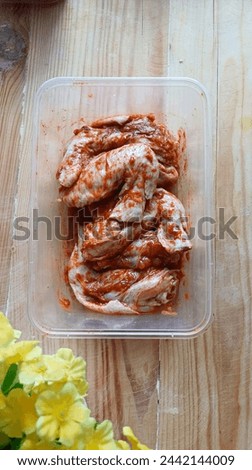 food preparation, raw spicy chicken stored in thinwall for frozen food stock makes cooking easier during ramadhan. isolated on wooden background 