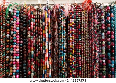 Strands of multicolored semiprecious stones offered for sale on display in bijouterie store Royalty-Free Stock Photo #2442157573