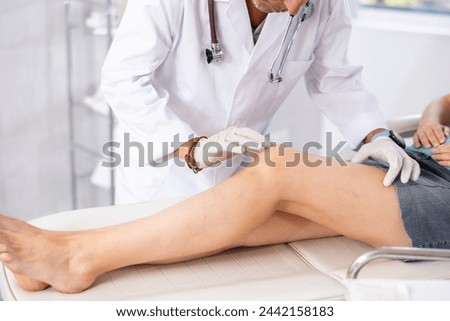 Attentive doctor man examining the sore knee of a female patient Royalty-Free Stock Photo #2442158183