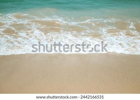 Soft waves of blue sea with foam on golden white sandy beach. Wave background