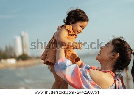 happy mother holding and lifting with her toddler baby girl on the sea beach Royalty-Free Stock Photo #2442203751