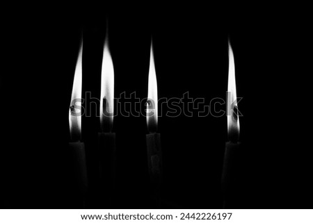 Minimalist picture of four candles with a black background. Black and white shot.