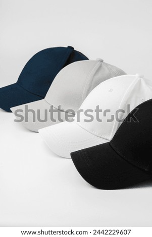 Four Baseball Caps in Black, White, Grey, and Blue Arranged on a Plain Background