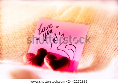 Fun picture on paper, notepad and two red hearts. Love you. Soft blurred light, atmospheric mood. Valentines Day