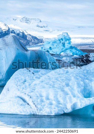 A large block of ice is surrounded by smaller blocks of ice. The scene is serene and peaceful, with the ice formations creating a sense of calmness Royalty-Free Stock Photo #2442250691