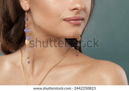 Gold necklace and long earring with blue and purple chalcedony and amethyst stones and pearl on jewelry model closeup Royalty-Free Stock Photo #2442250823
