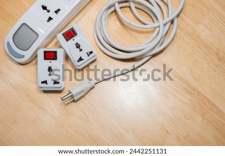 White power extension lead with multiple sockets on wooden table. Top view, copy space. Royalty-Free Stock Photo #2442251131