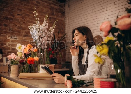 Young beautiful hispanic woman florist smiling confident using touchpad and laptop at florist. High quality photo