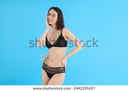 Slim girl in underwear with flowers, on a blue background.