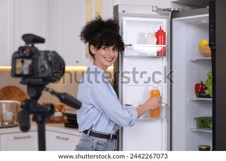 Smiling food blogger explaining something while recording video in kitchen Royalty-Free Stock Photo #2442267073