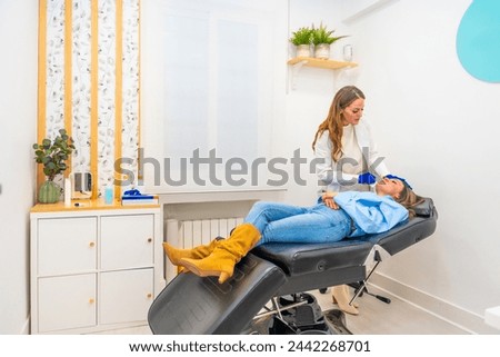 Cosmetologist working in a innovative beautician clinic injecting hyaluronic acid to the face of a woman