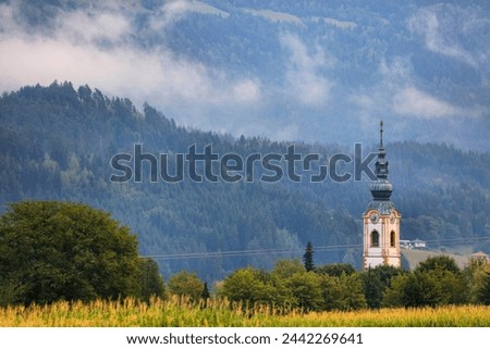 Misty forest layers in Gailtal Alps. Mountain view with church tower after rain in Carinthia region of Austria. Royalty-Free Stock Photo #2442269641