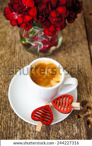 Cup of coffee and red cloves flowers in a vase with good morning note