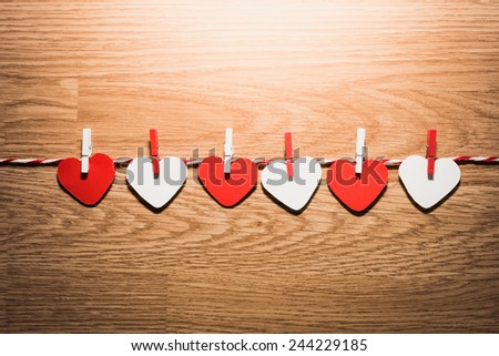 Love Valentine's hearts natural cord and red clips hanging on rustic driftwood texture background, copy space