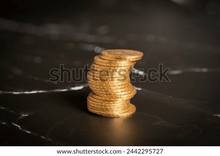 Close-up view stack of golden Louis coins on a black and white marble surface