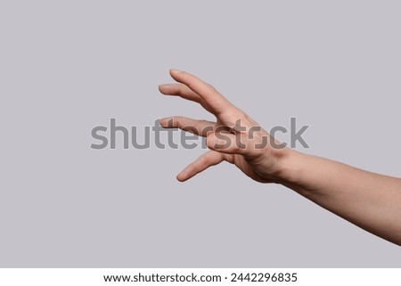 Close up of hand trying to reach for someone or something. Gesture of asking help or sign for lust isolated on light gray background. Right hand. Royalty-Free Stock Photo #2442296835