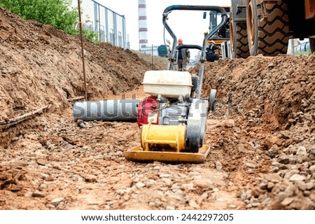 A yellow and black machine is actively working in dirt and soil, displaying signs of heavy use and functionality.